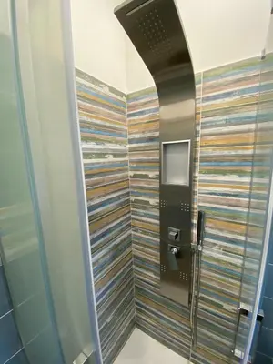 a bathroom with a shower with a colorful wall at IN CENTRO ROOMS Vicino Cefalù SELF-CHEK-IN in Campofelice di Roccella