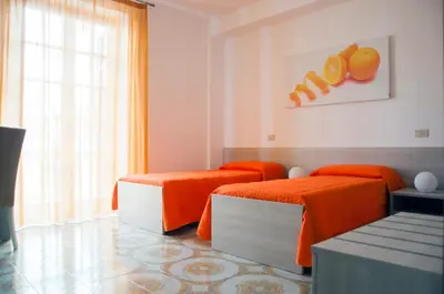 a room with two beds with orange sheets at Alto Giardino Rooms in Terrasini