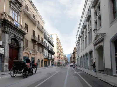 a horse drawn carriage driving down a city street at Maqueda331 in Palermo