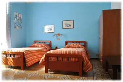 two beds in a bedroom with a blue wall at Bed and Breakfast D'Angelo in Palermo