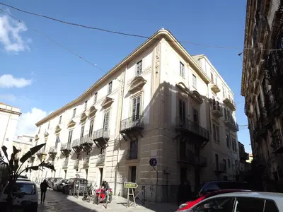 a large white building with cars parked on a street at I Cavalieri di Malta in Palermo