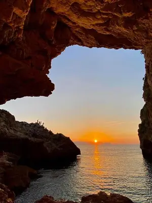 a view of the sunset from a cave in the ocean at La Caletta Casa Vacanze, PRIVATE POOL in Terrasini