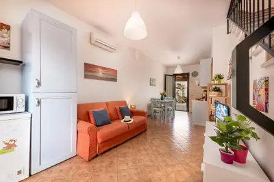 a living room with an orange couch and a kitchen at Carlottas Home in San Vito lo Capo