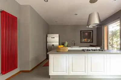 a kitchen with white cabinets and a red curtain at Il Giardino di Michela by DomuSicily in Mondello