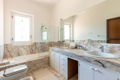 a bathroom with two sinks and a tub and two mirrors at Il Giardino di Michela by DomuSicily in Mondello