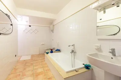 a white bathroom with a tub and a sink at Il Giardino di Michela by DomuSicily in Mondello