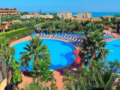 an overhead view of a pool with chairs and palm trees at Residence in Sicily near Himera & Madonie Park in Buonfornello