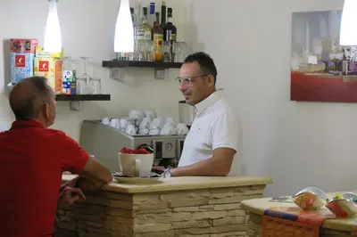 a man sitting at a counter talking to a man at Trigrana Vacanze Hotel in Castelluzzo