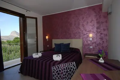 a bedroom with a bed with two bags on it at Trigrana Vacanze Hotel in Castelluzzo
