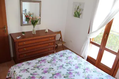 a bedroom with a bed and a dresser with a vase of flowers at Villetta con giardino Mandarino Macari in Macari