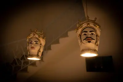 two masks hanging on a wall with lights at Cocciu d'amuri in San Vito lo Capo