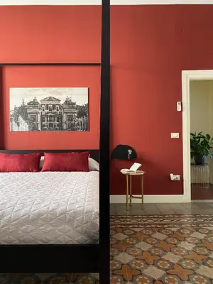 a bedroom with a red wall and a bed at B&B Palazzo Corselli in Bagheria
