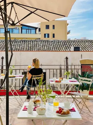 a woman sitting at a table on a balcony with food at B&B Palazzo Corselli in Bagheria