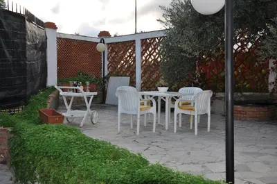 a patio with white chairs and a table in a yard at Corso's old nest a mille metri dalla spiaggia guida loca in Castellammare del Golfo