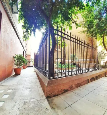 a wrought iron fence with a tree next to a building at A un passo dal centro in Palermo