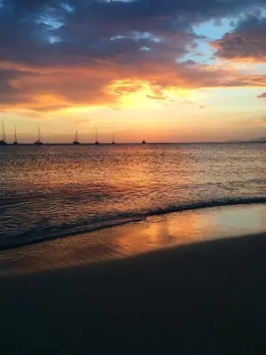 a sunset on the beach with sailboats in the water at Casa Mandarino in Macari