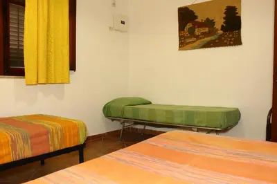 a room with two beds and a yellow curtain at Villa Porto Rais in Carini