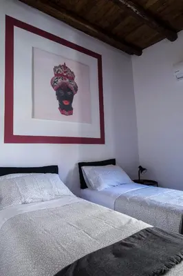 two beds in a room with a picture on the wall at La Casa del Moro in Palermo