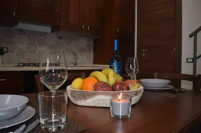 a table with a bowl of fruit and a bottle of wine at Casa Vacanza Mar' illù in Castellammare del Golfo
