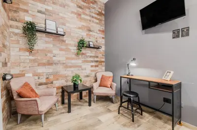 a room with two chairs and a desk and a television at Panurban Rooms by Wonderful Italy in Palermo