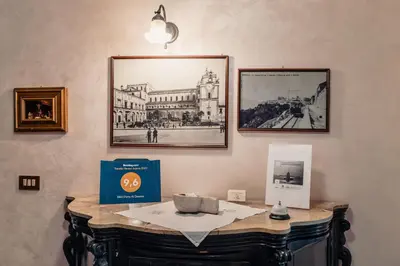 a table with a box and pictures on the wall at B&B Elvira Al Duomo in Monreale