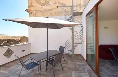 a table and chairs with an umbrella on a balcony at Veranda sul Mare in Castellammare del Golfo