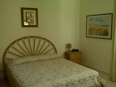 a bedroom with a bed and a picture on the wall at Villetta immersa nel verde ma vicina al mare in Lascari