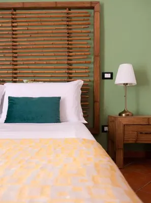 a bedroom with a bed with a wooden headboard and a lamp at Kalamarina Rooms in Palermo