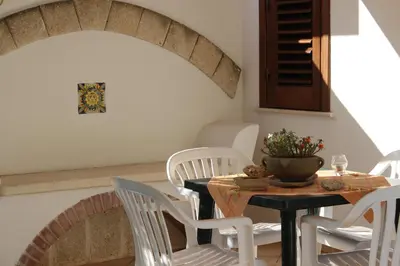 a dining room with a table and white chairs at Monolocale da Mariolina in Macari