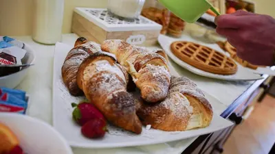 two plates of pastries on a table with a person holding a cup at LE PORTE DI PALERMO in Palermo