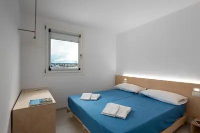 a bedroom with a blue bed and a window at Vitop Residence in San Vito lo Capo