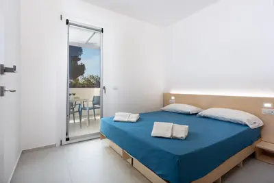 a bedroom with a blue bed and a balcony at Vitop Residence in San Vito lo Capo