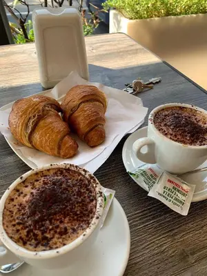a table with a plate of croissants and a cup of coffee at Leone Suite B&B & Restaurant AIC in Palermo