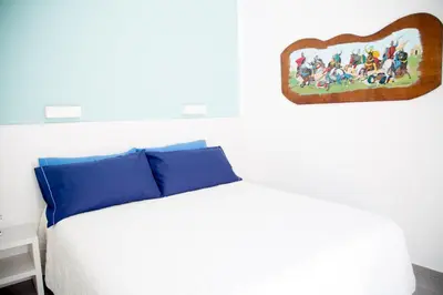 a bedroom with a bed with a painting on the wall at White Asses Rooms in Castellammare del Golfo