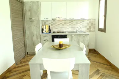 a kitchen with a table and white chairs in it at Suite Capaci in Capaci