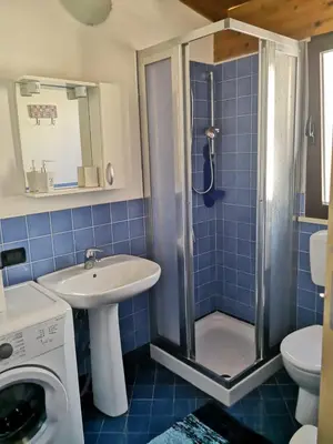 a blue tiled bathroom with a shower and a sink at La casetta in Terrasini