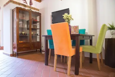 a dining room table with green chairs and a television at Mau House 44 Apartment in Palermo
