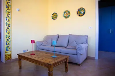 a living room with a blue couch and a coffee table at Solemar Sicilia - Casa Enza in Santa Flavia
