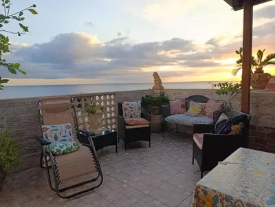 a patio with chairs and tables and a view of the ocean at Torre Vallelunga in Trabia