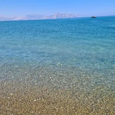 a beach with clear blue water and a boat in the distance at Sea Room Aspra in Bagheria