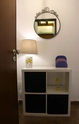 a table with a lamp and a mirror on a wall at Mondello Apartment in Mondello
