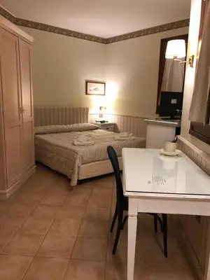 a bedroom with a bed and a table and a desk at Krimar Hotel in San Vito lo Capo