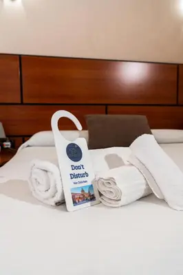a pile of towels and a book on a bed at Hotel City Center in Palermo