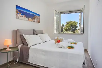 a bedroom with a white bed and a window at Casa del Melograno con idromassaggio e giardino in Terrasini