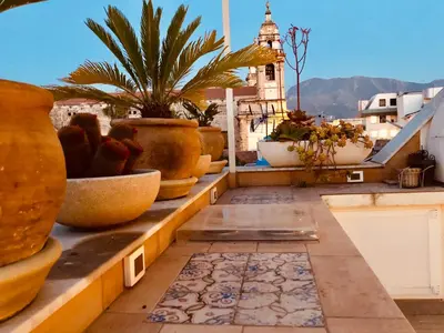 a balcony with potted plants and a clock tower at Gagini House & Terrace in Palermo