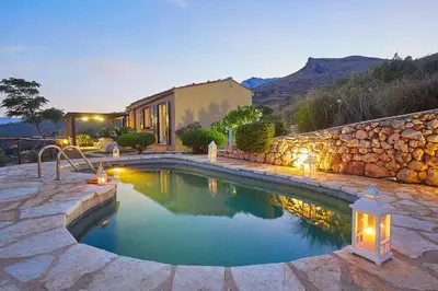 a swimming pool in a yard with a stone wall at Villa Delfino - Scopello-Villas in Scopello