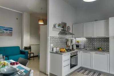a kitchen with white cabinets and a blue couch at Annina'S Home Panoramic sea view By Sicily Home Solutions in Castellammare del Golfo