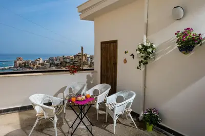 a table and chairs on a balcony with a view of the ocean at Annina'S Home Panoramic sea view By Sicily Home Solutions in Castellammare del Golfo
