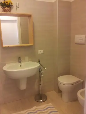 a bathroom with a sink and a toilet and a mirror at Essenzamare in San Vito lo Capo