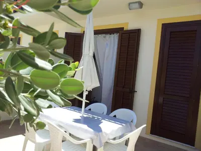 a table with an umbrella and chairs and a plant at Essenzamare in San Vito lo Capo